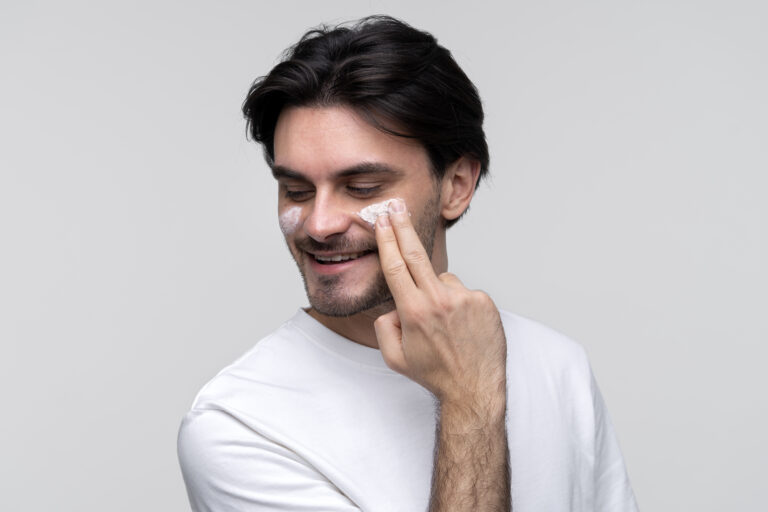portrait young man applying moisturizer his face